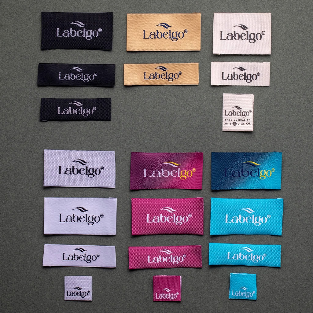Assorted colorful woven labels spread on fabric surface.