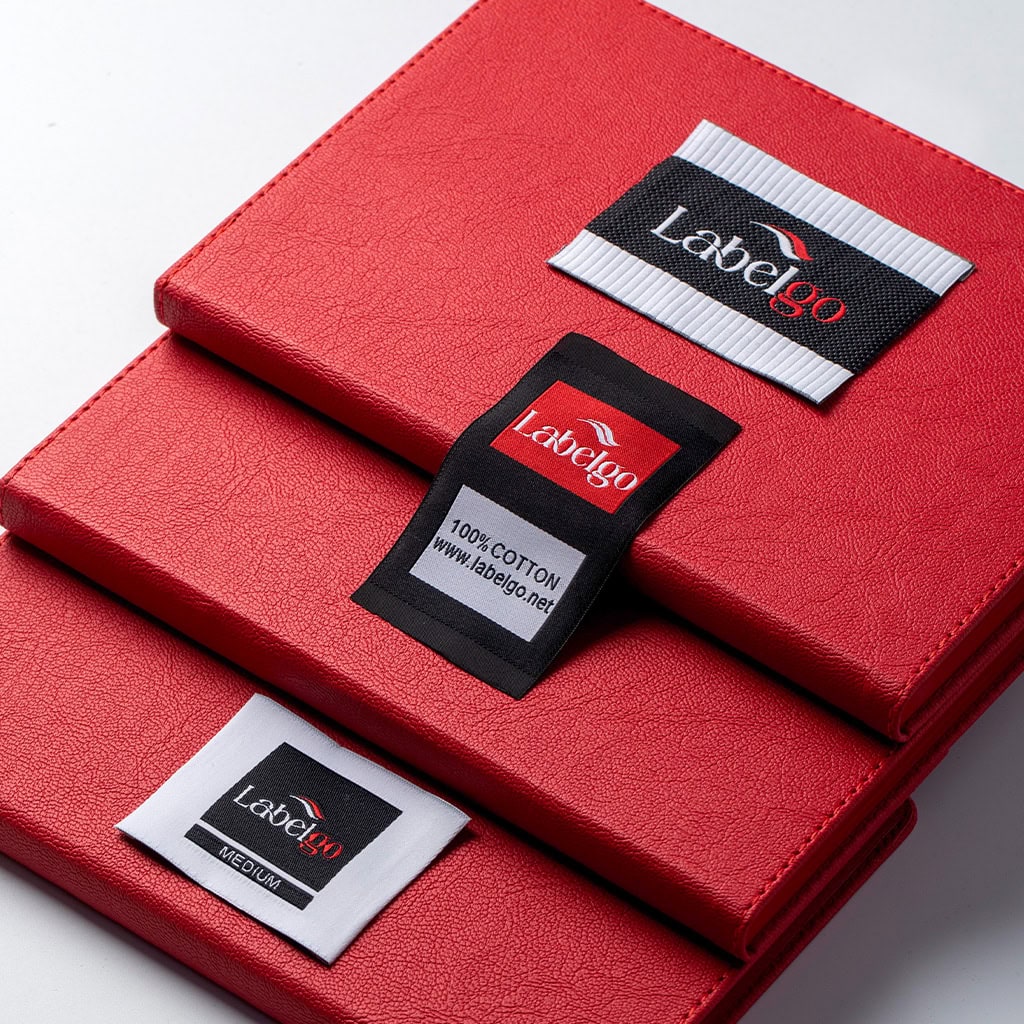 Black and red woven clothing labels arranged on red fabric.